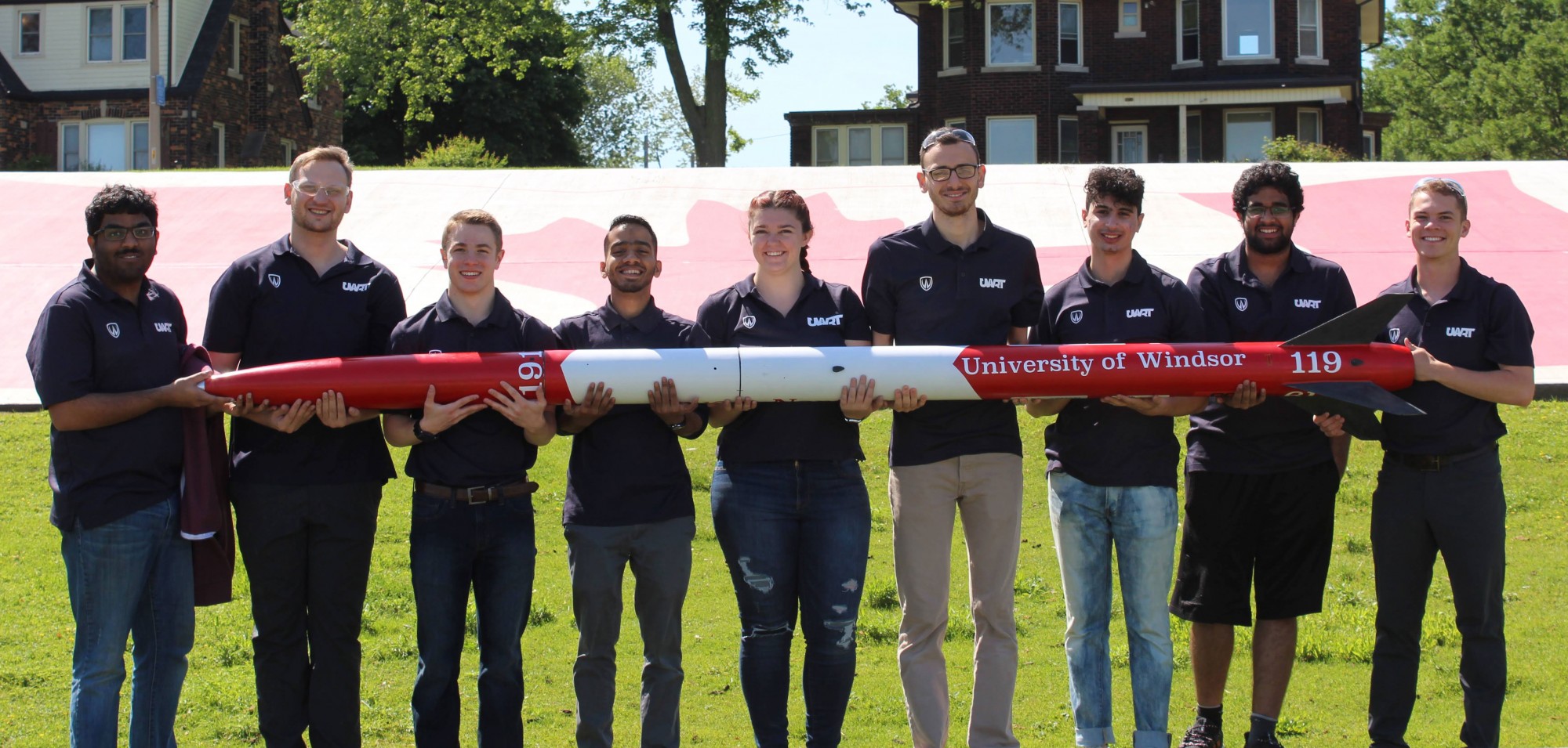 A team of mechanical engineering students holding rocket.