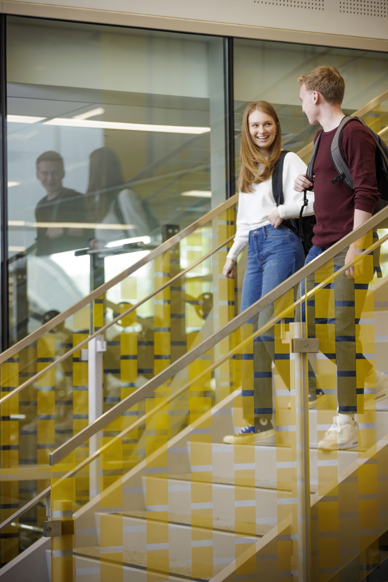 A male and female student walk down a staircase
