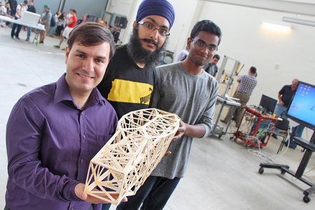 Students hold popsicle stick bridge model