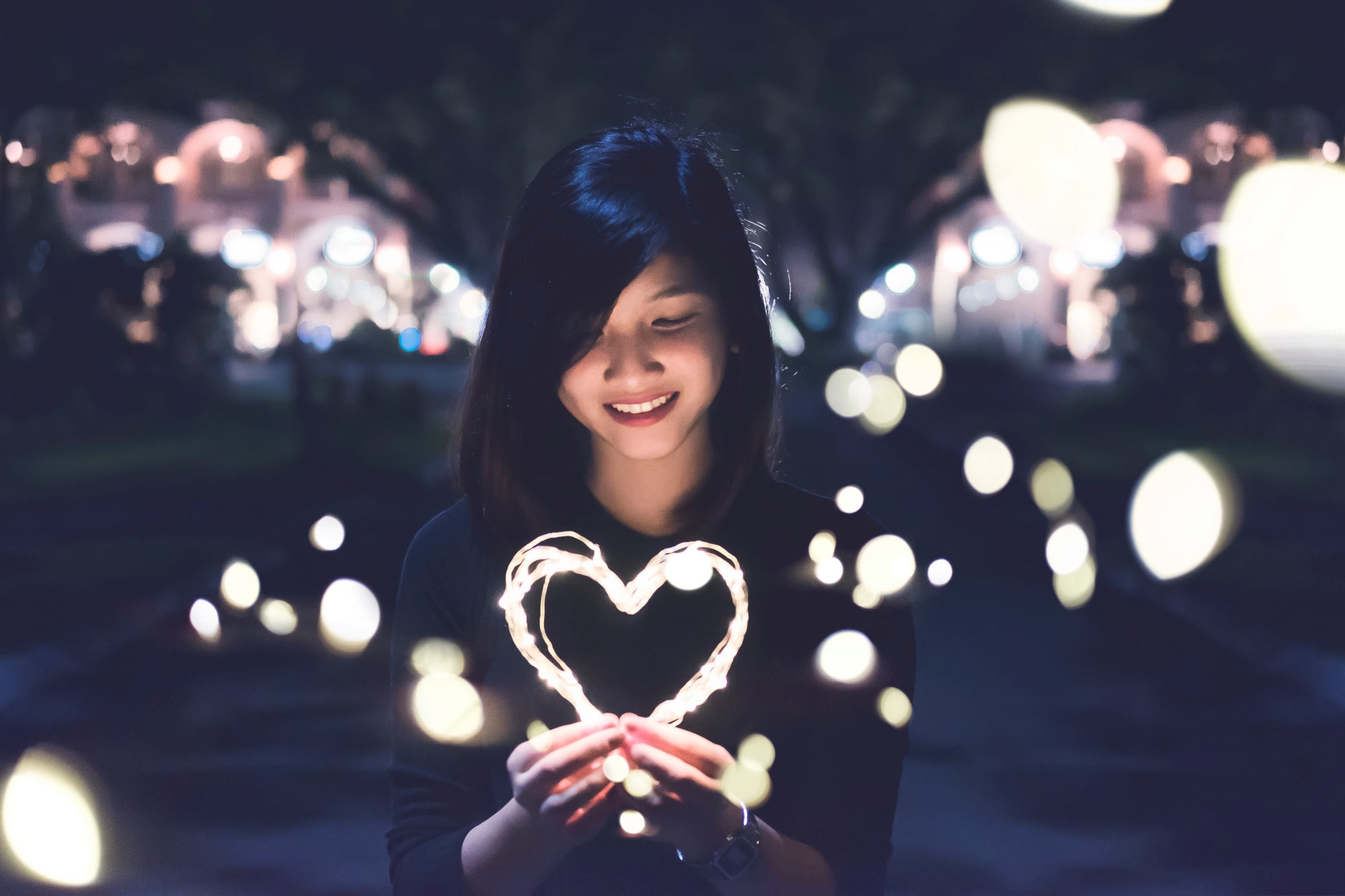 Young woman holding a heart made of twinkle lights