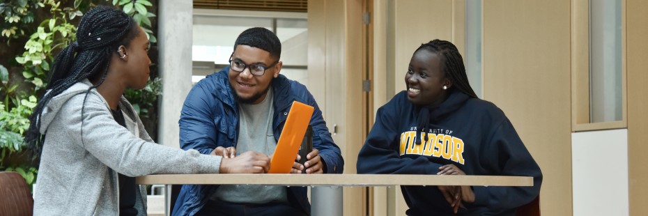 Three students working around a laptop