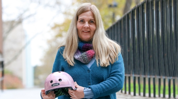 Professor Lori Buchanan holds a bicycle helmet, painted as part of the Brain Bucket research project of recent Master’s graduate Daniella Mlinarevic.