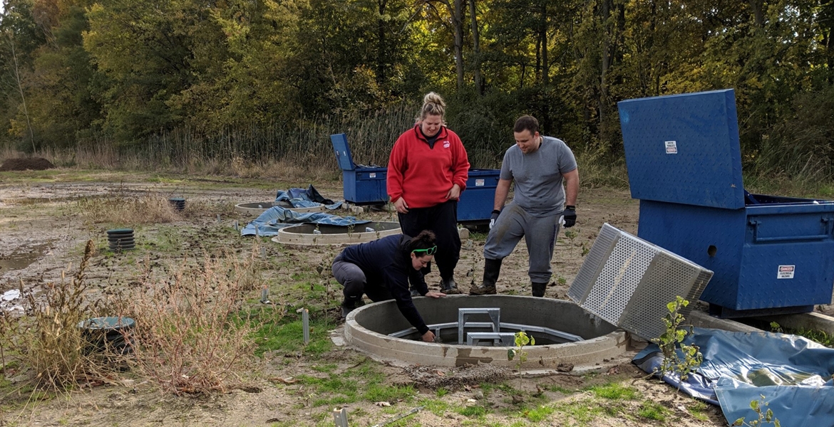 Watershed research technicians Mackenzie Porter and Samantha Dundas of the Essex Region Conservation Authority and biochemistry student Dave Ure clear a biofilter at the Lebo Creek Wetland.