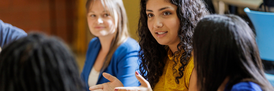 Student talking at a table with other students