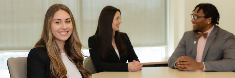 Student smiling at camera with two students talking in the background