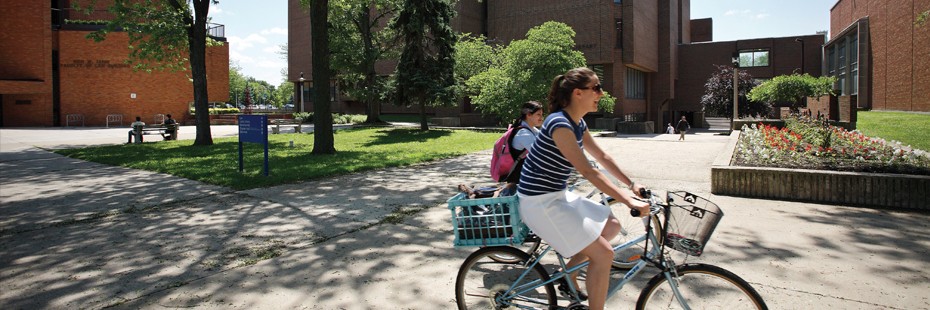 Two students riding bicycles on campus