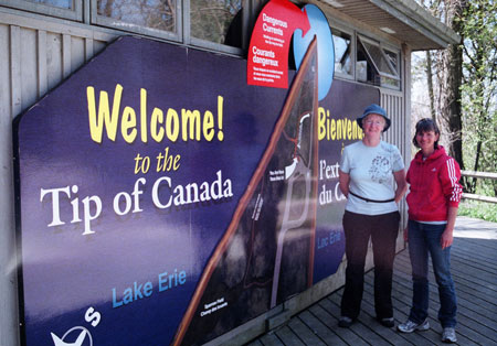 Alison Holmes and Marie-Jeanne Monette by large sign that reads: Welcome to the Tip of Canada.