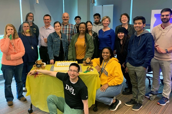 professionals gathered around celebratory cake