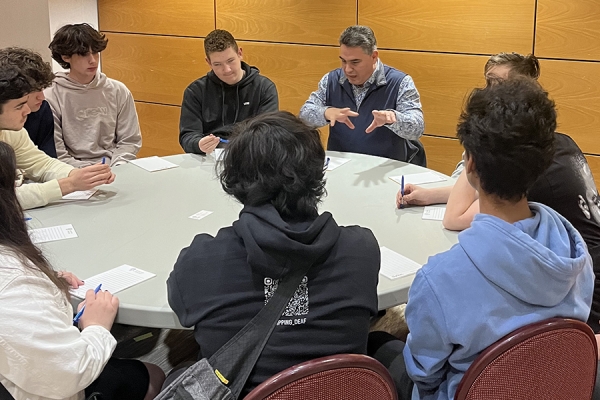 professor in animated discussion with roundtable of students