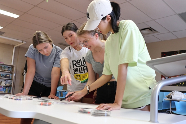 High school girls consider a challenge laid out on a labratory table