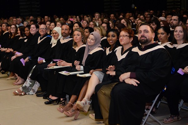 grads in gowns awaiting their turn on stage