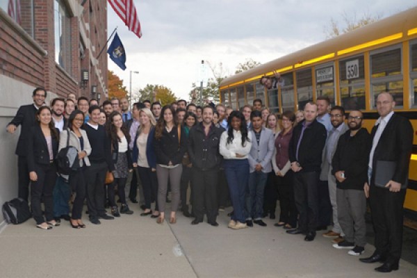 students stand on sidewalk outside bus