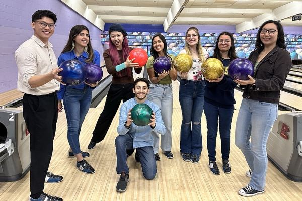 Quoc Viet Truong, Zeina Haider, Jiasi Liu, Chelsea Ymana, Lyla Pratt, Maria Oliveira, Ashley Jun, and Khaled Al Khatib hold bowling balls.