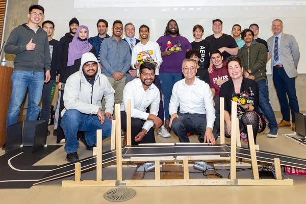 students and faculty standing in model obstacle course