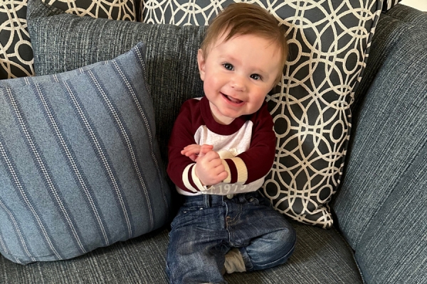 young baby propped up on sofa with cushions