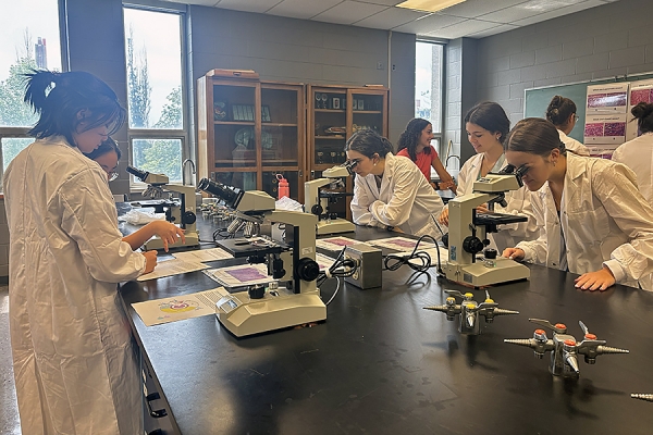 students peering into microscopes