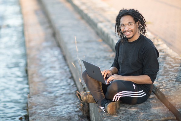 Chris Boyd sitting next to river with laptop computer