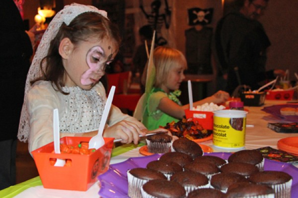 girl spreading icing on a cupcake