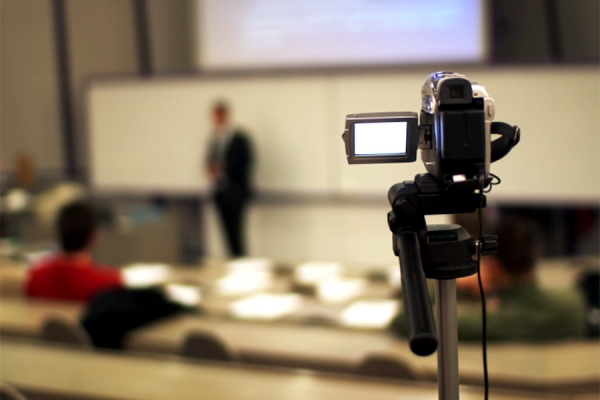 instructor standing before class seen through video camera