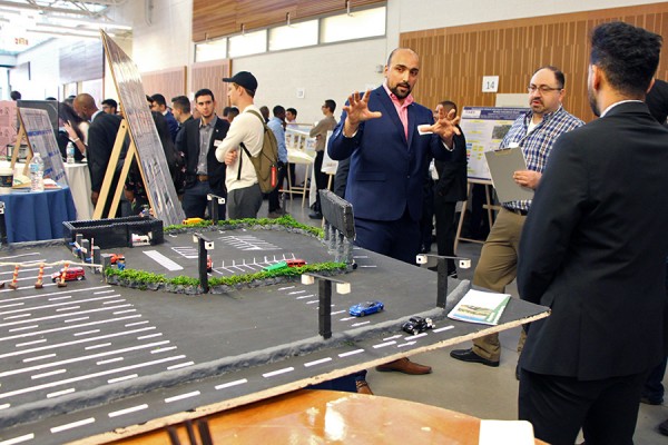 Habib Haider explains his group project, a system designed to reduce the impact of long lines waiting to access the Gordie Howe International Bridge, to professor Hanna Maoh of the Cross-Border Institute.