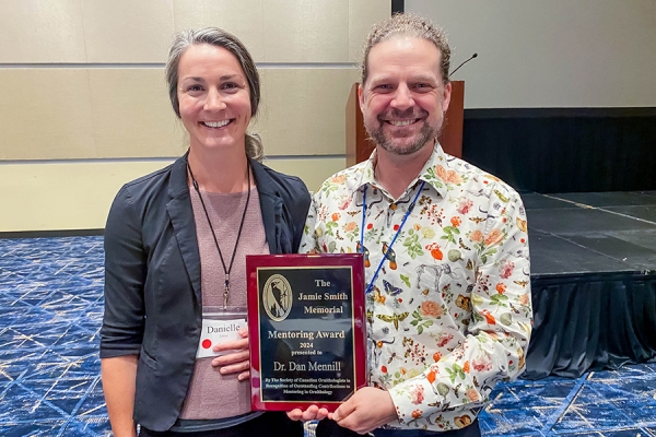 Society of Canadian Ornithologists president Danielle Ethier confers an award on Dan Mennill