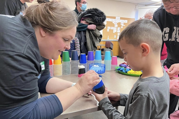 Teacher candidate Kristina Bailey demonstrating craft activity to child