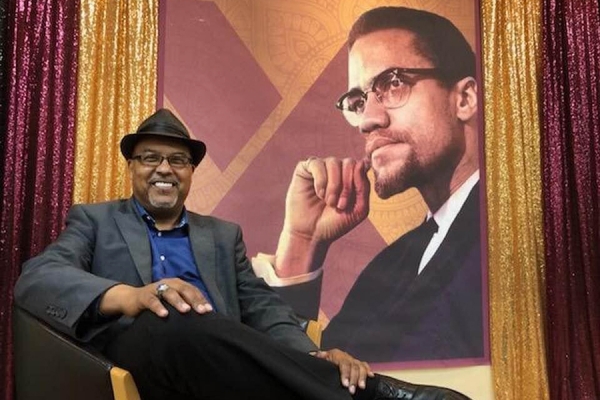 Abdur-Rahman Muhammad before portrait of Malcolm X