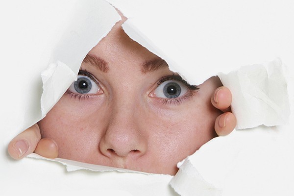 face peering through torn paper