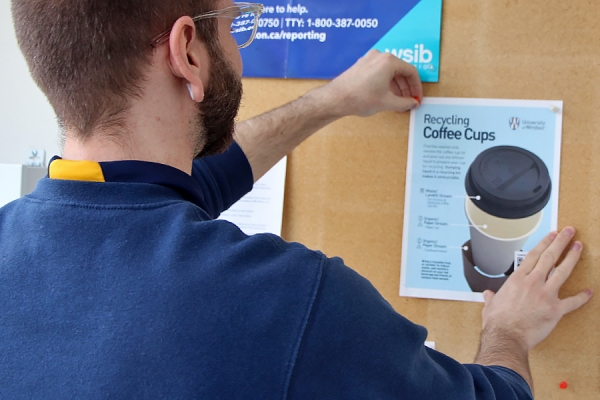 man tacking recycling poster to bulletin board