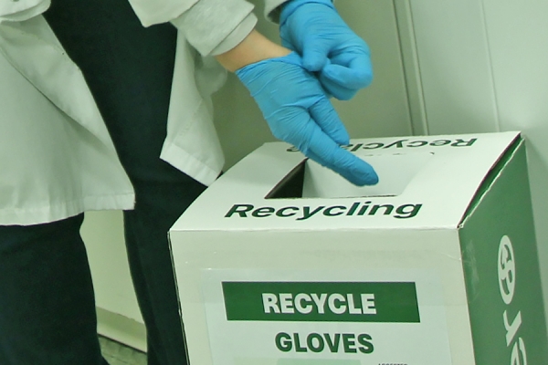 hands stripping off lab gloves for recycling