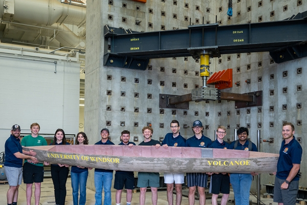 team members hold concrete canoe