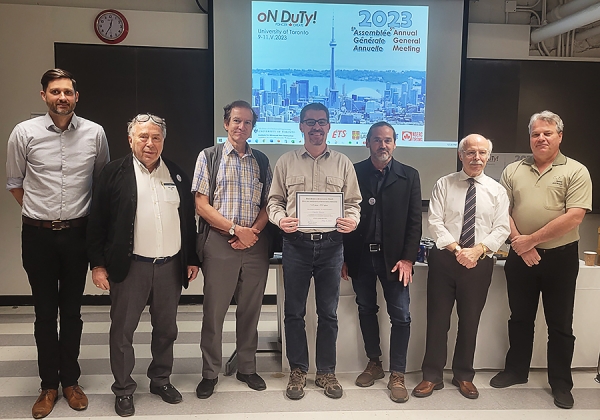 Line up of men; the middle one is holding an award certificate