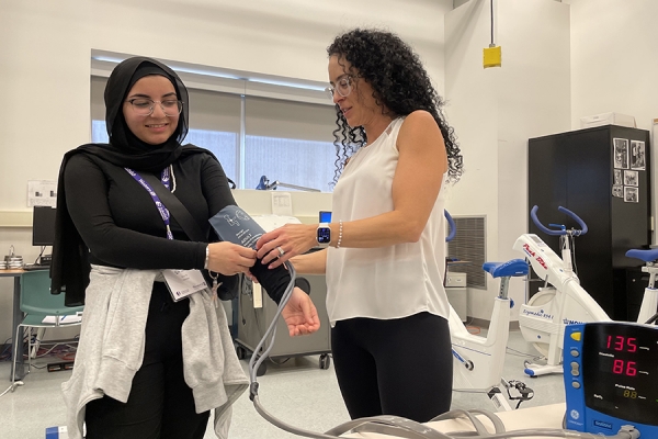 woman secures blood pressure cuff to student arm