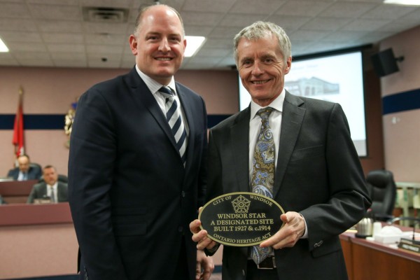 Windsor Mayor Drew Dilkens presents University of Windsor President Alan Wildeman with a heritage plaque for the rehabilitation of the former Windsor Star.