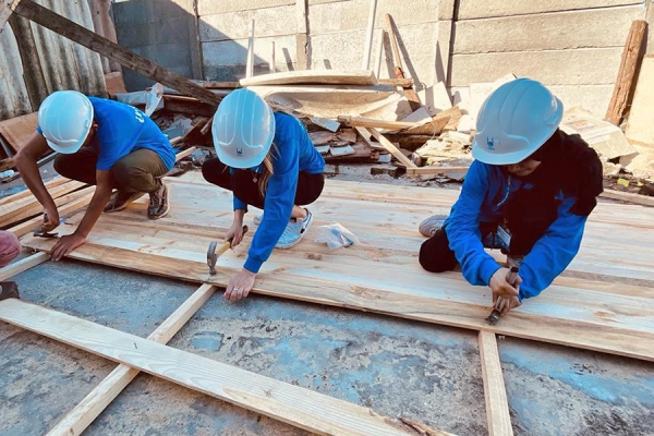 Volunteers hammer lumber to repair a wall.