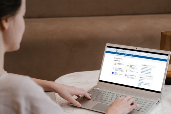 Women sitting at a table with laptop displaying the service UWindsor catalogue screen.