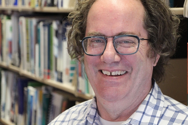 Martin Deck smiling with shelves of books behind him.