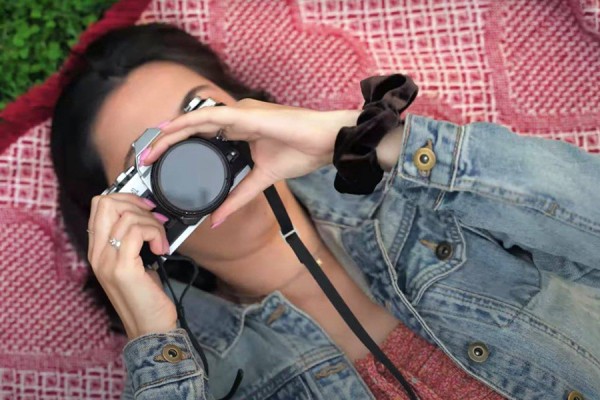 still from “Starving Artist” by Dominique Nickels; young woman lying on back holding camera to her eye