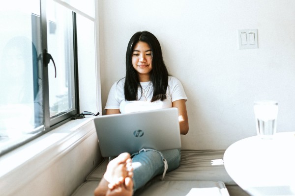 A student works on her laptop near a window at home.