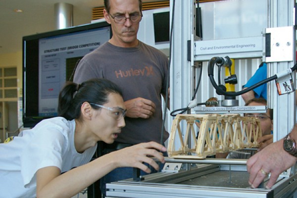 Technologist Matt St. Louis helps students set their model bridge in a special machine to measure its ability to support weight. 