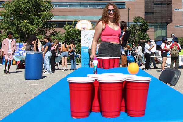woman bouncing ball into cup during Involvment Fair activity
