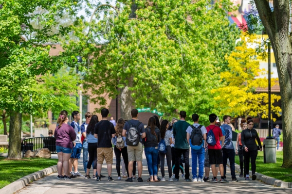 group of students at outdoor event under leafy trees