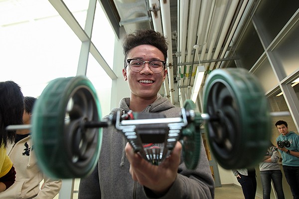 A participant in the High School Design Competition shows off his model vehicle.