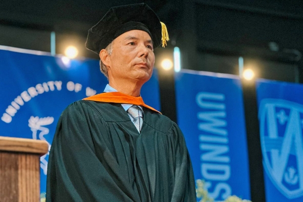 Jonathan Wu stands on stage at Convocation