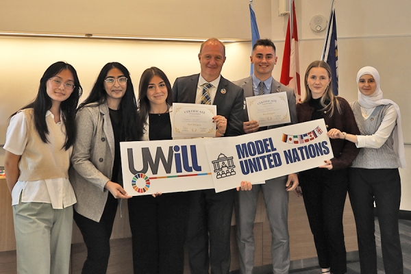 people hold sign reading UWill Discover Model United Nation