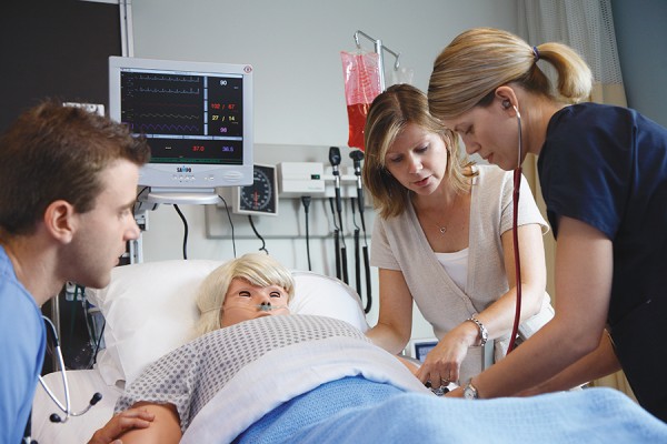 nursing professor working with students on patient simulator