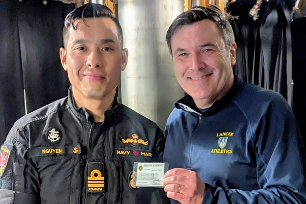 Harrison Nguyen-Huynh of the HMCS Windsor presents honorary submariner credentials to Mike McKay