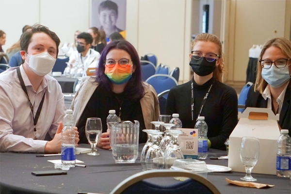 Conferees wearing masks gathered around table