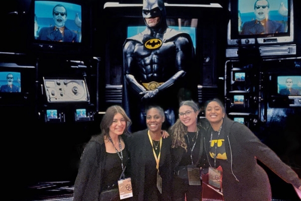 four students lined up in front of projection of Batman