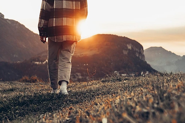 person walking toward sunrise